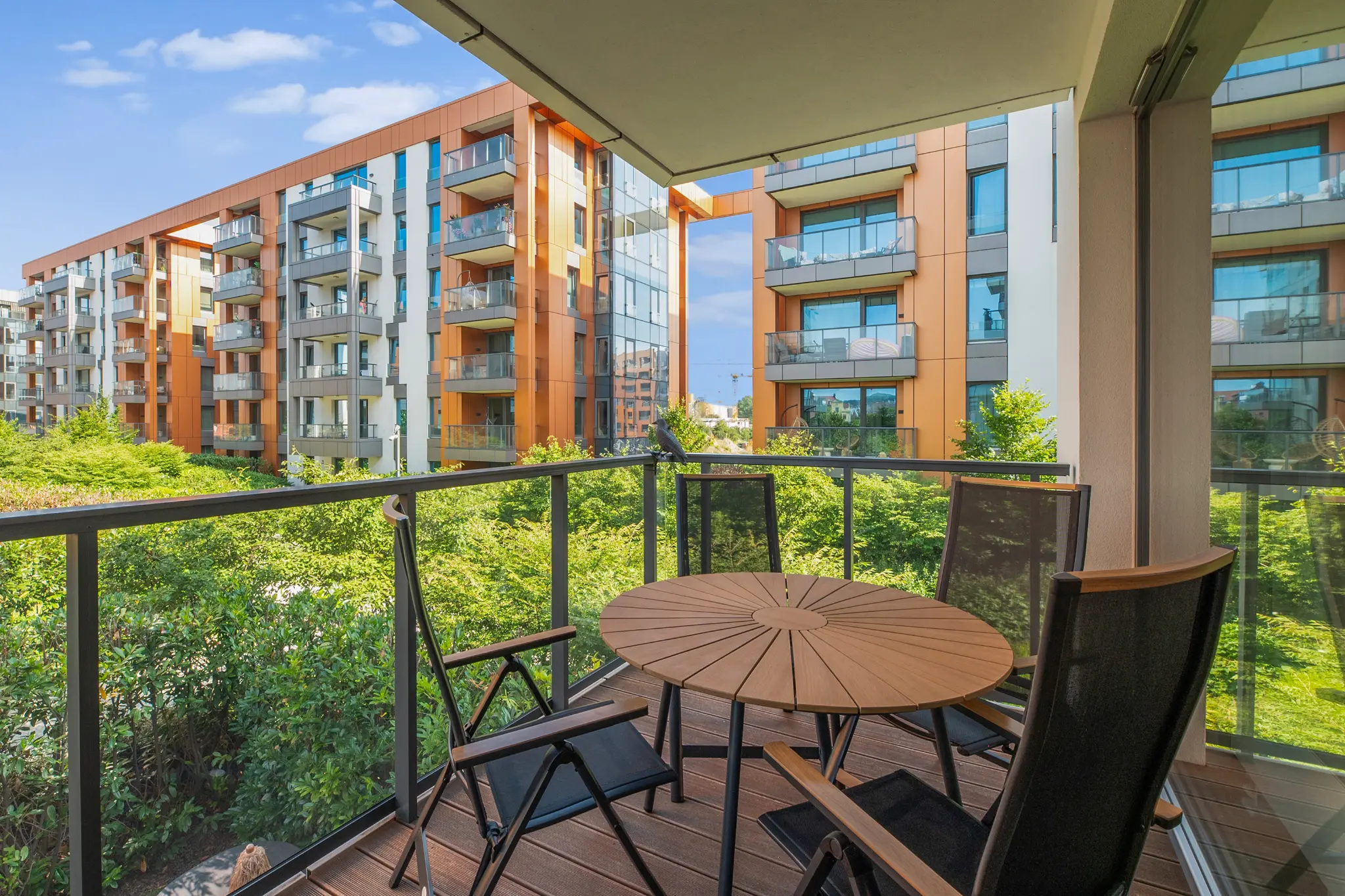 Balkon apartamentu Brabank ze stołem i krzesłami oraz widokiem na zielony dziedziniec