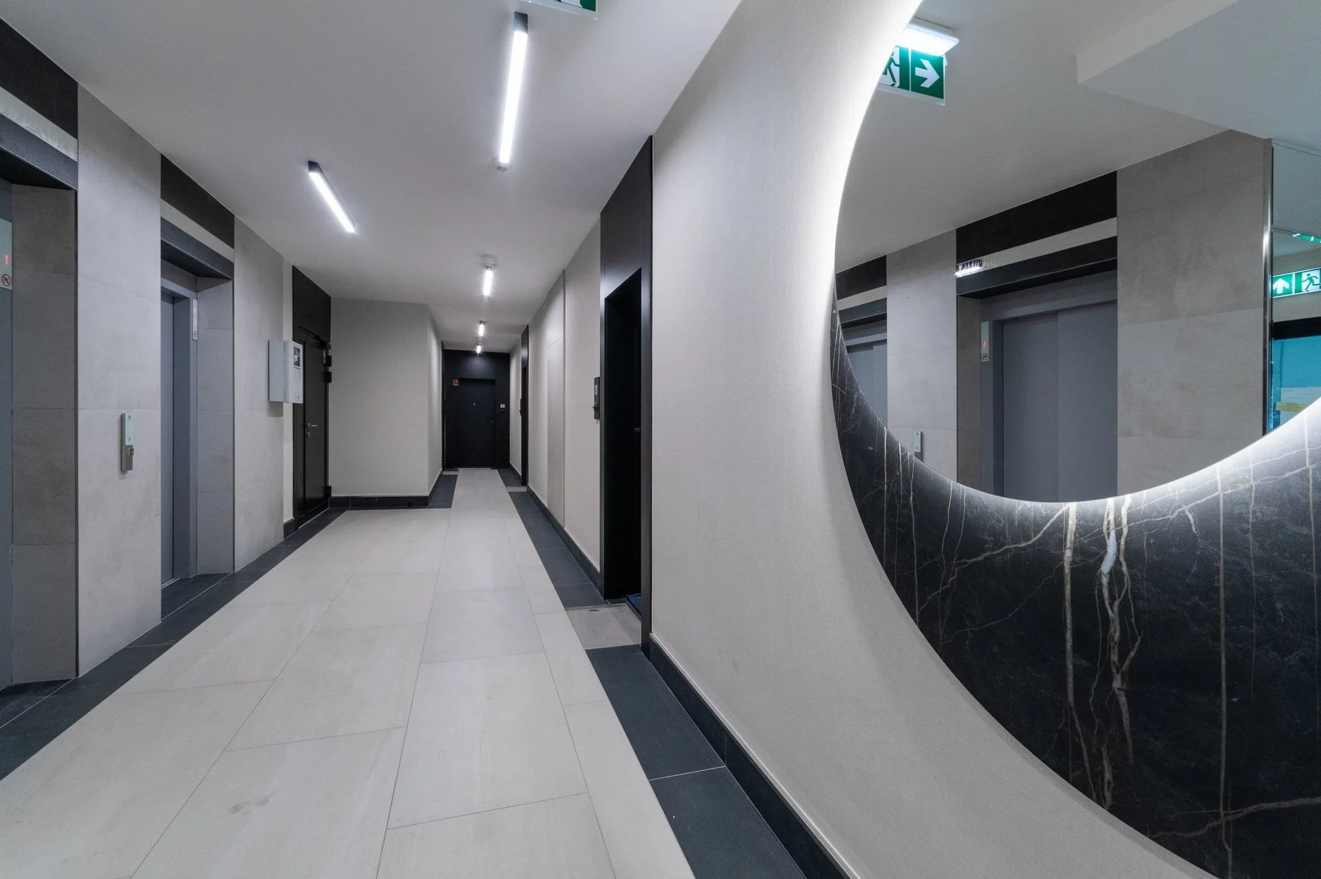 Common areas at Bulvar Apartments — hallway with lifts, lighting and a large round mirror