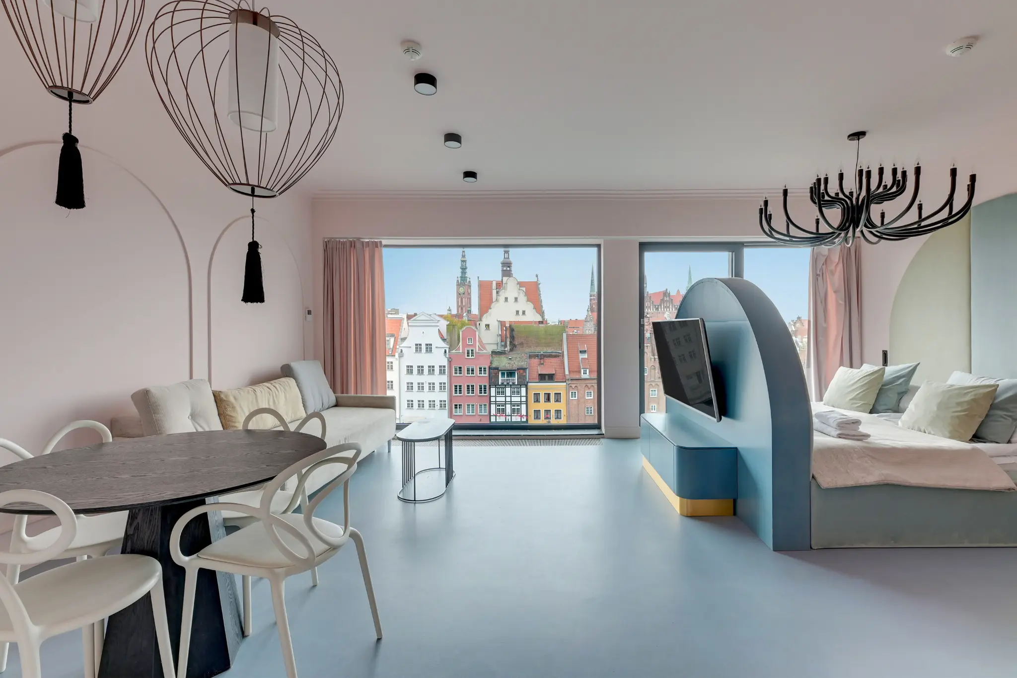 Salon i strefa snu w apartamencie Deo Plaza, pastelowa zabudowa i duże okna na Gdańsk