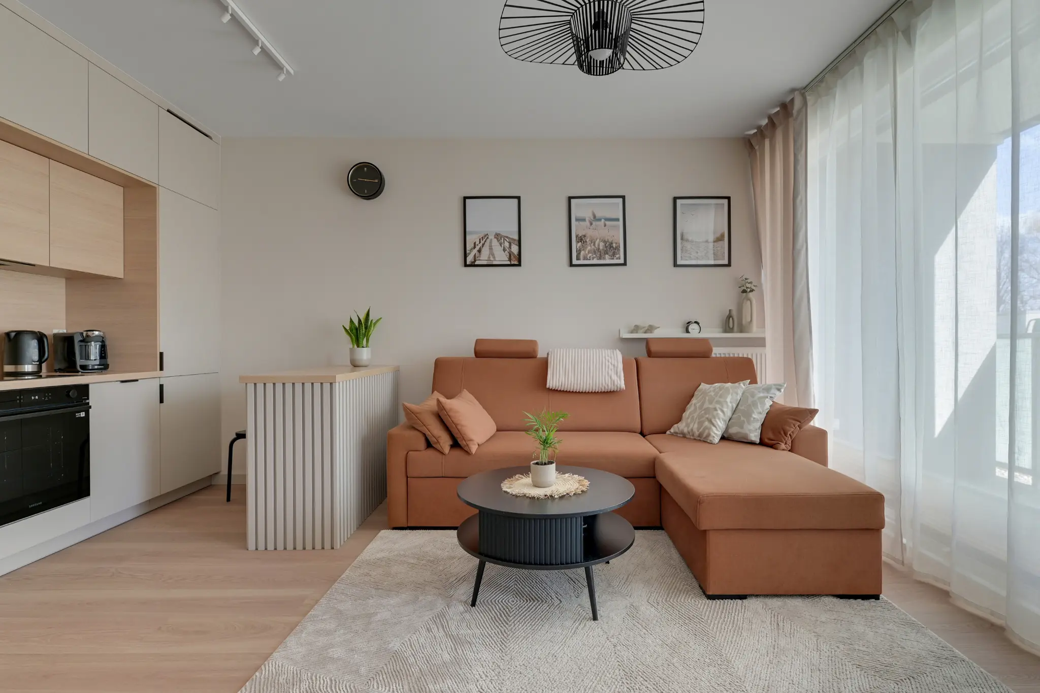 Salon apartamentu w Horizonie — ruda sofa, aneks kuchenny i duże okna
