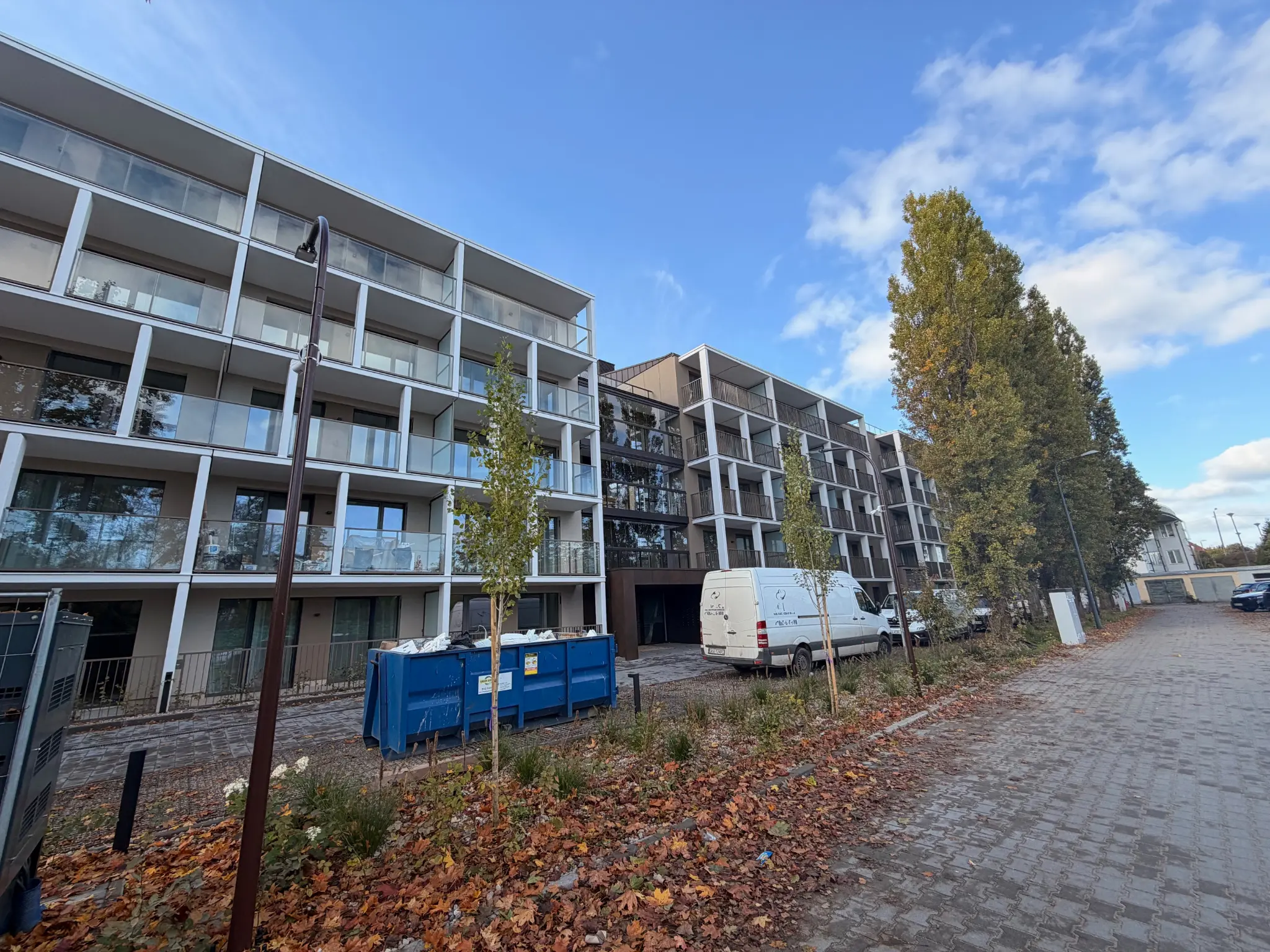 Broader view of Kolna Sopot buildings with balconies, vehicles and materials during work