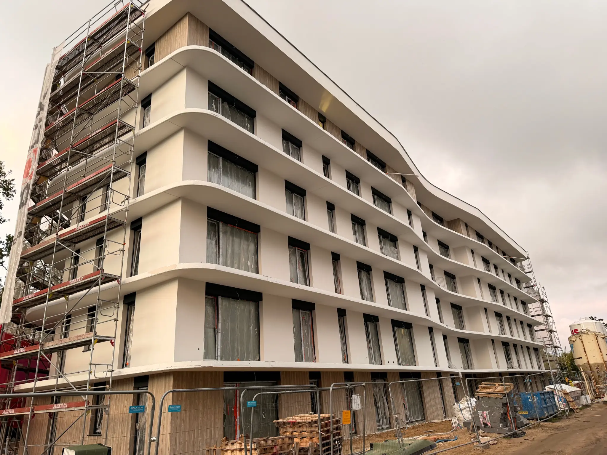 Letnicka Residence w budowie — jasna elewacja, zaokrąglone balkony i rusztowania