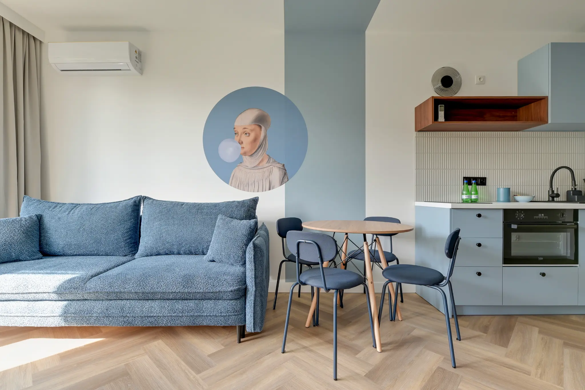 Living room with a blue sofa, table and kitchenette in an apartment on Mostek Street