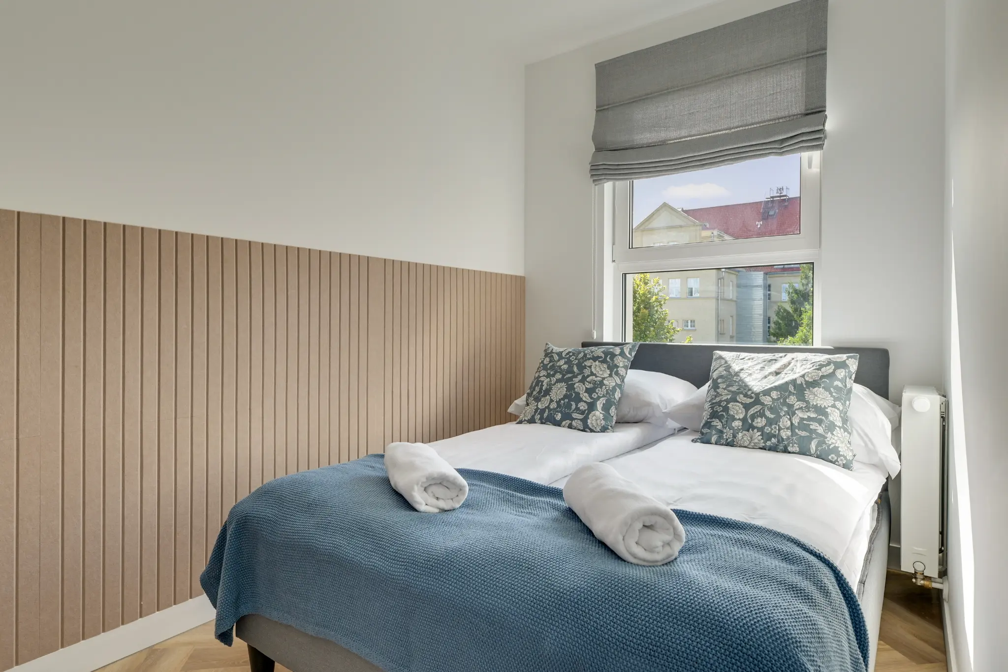 Bedroom with a wooden wall and blue bedspread in an apartment at Mostek