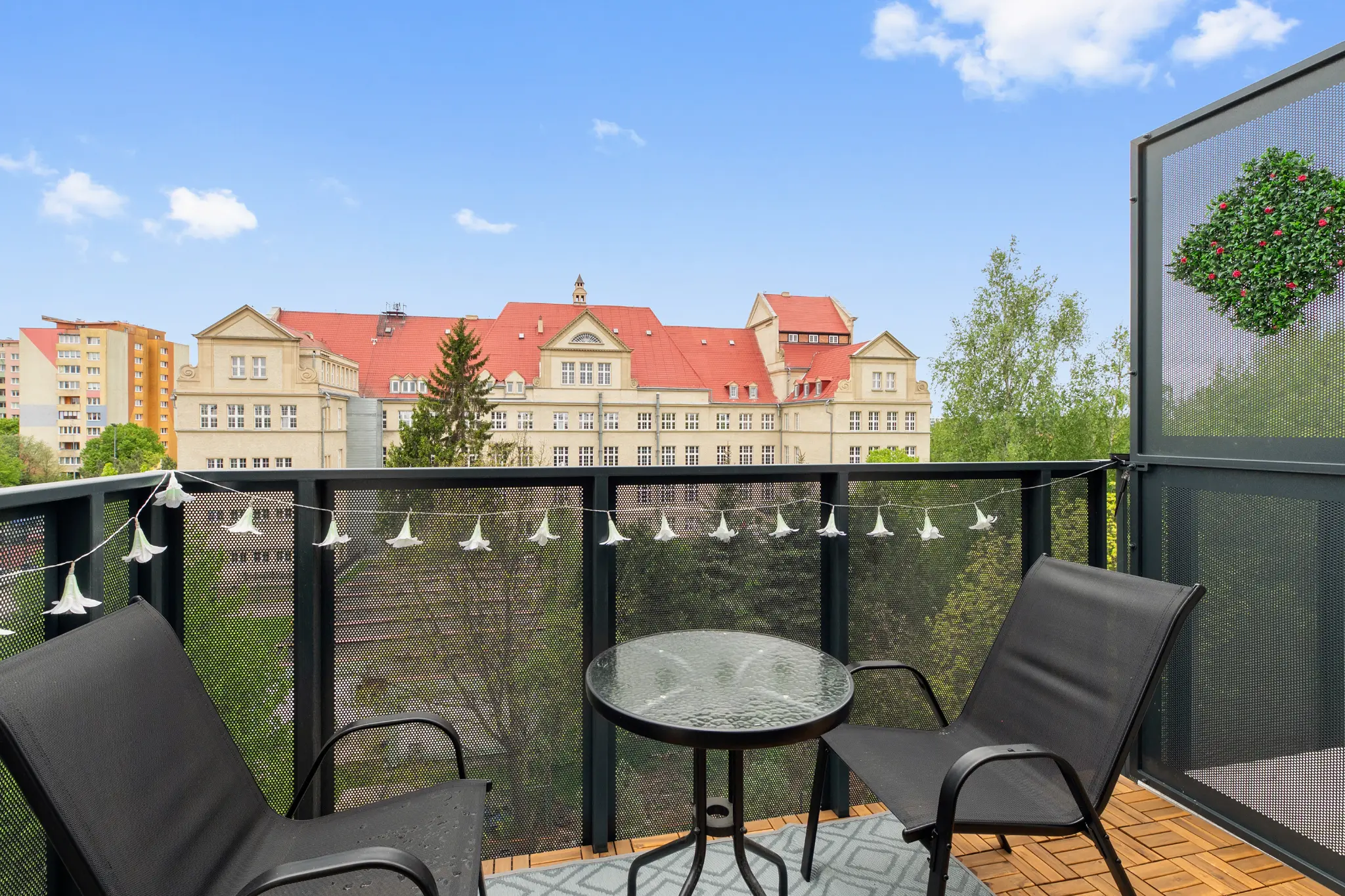 Balcony with a table and a view of a neighbouring building with a red roof