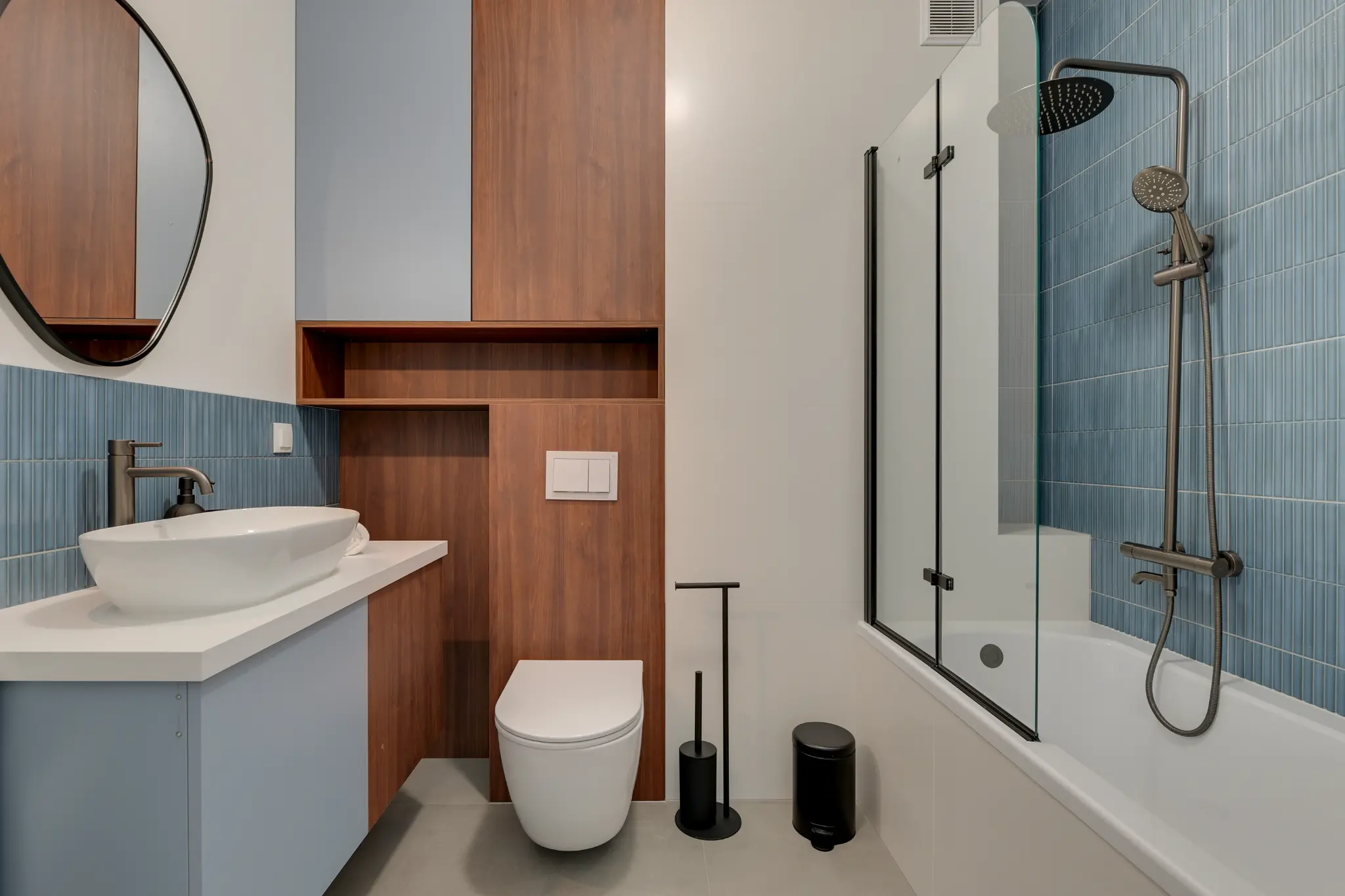 Bathroom with blue tiles, washbasin and bathtub with a glass screen