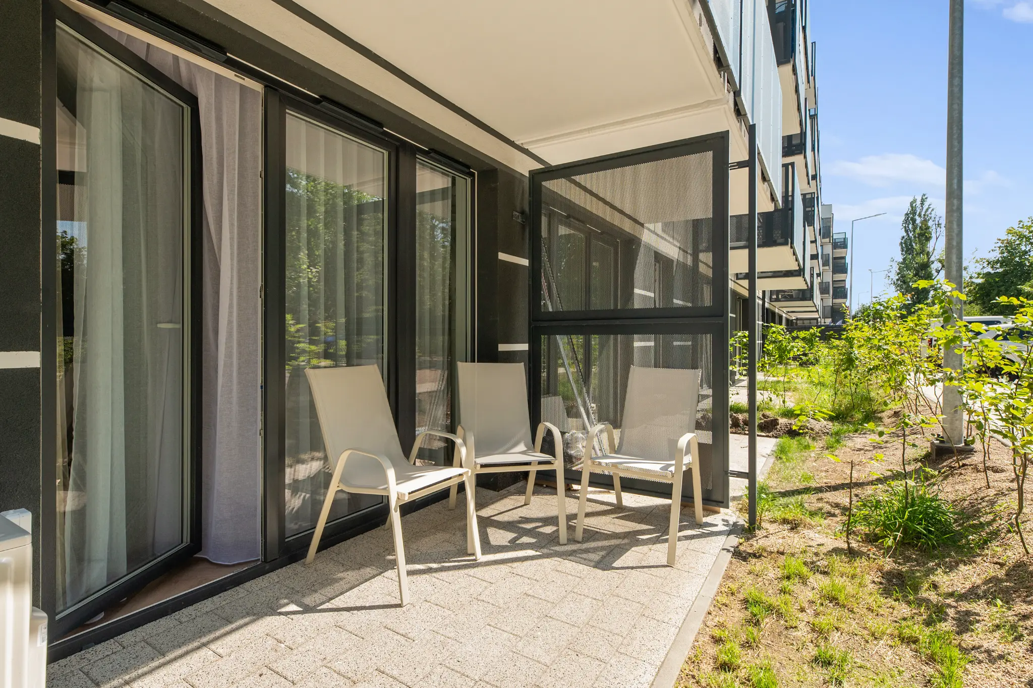 Apartment terrace with chairs and a table beside greenery in Portovo