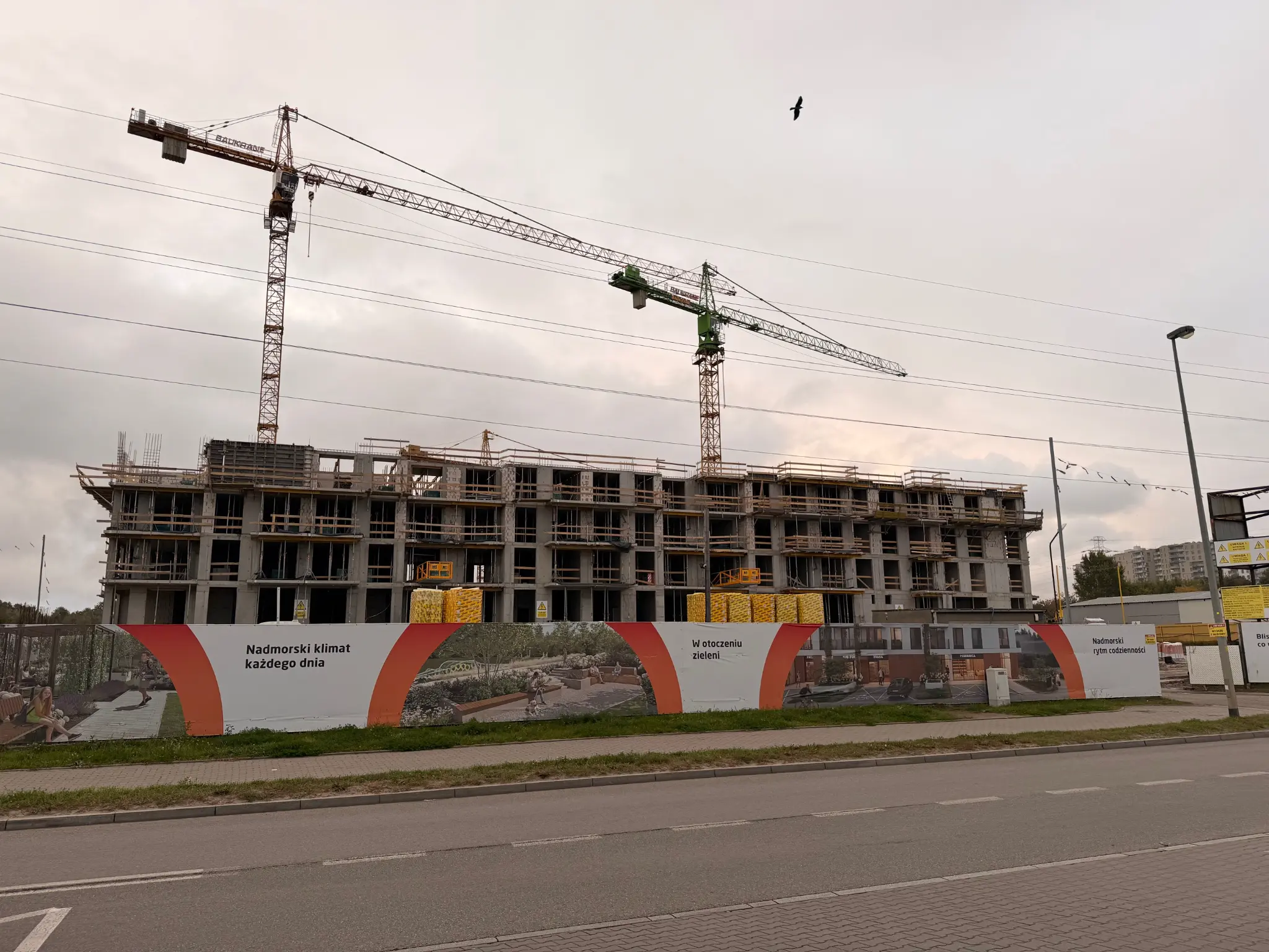 Przystań Brzeźno under construction — building structure, cranes and fencing by the street