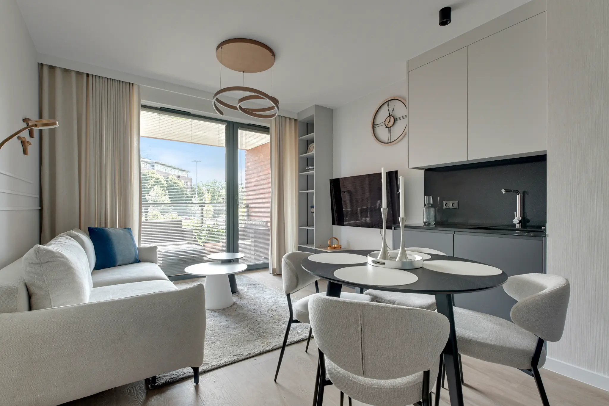Living area of a Scala apartment — a light sofa, kitchenette and an oval table with upholstered chairs