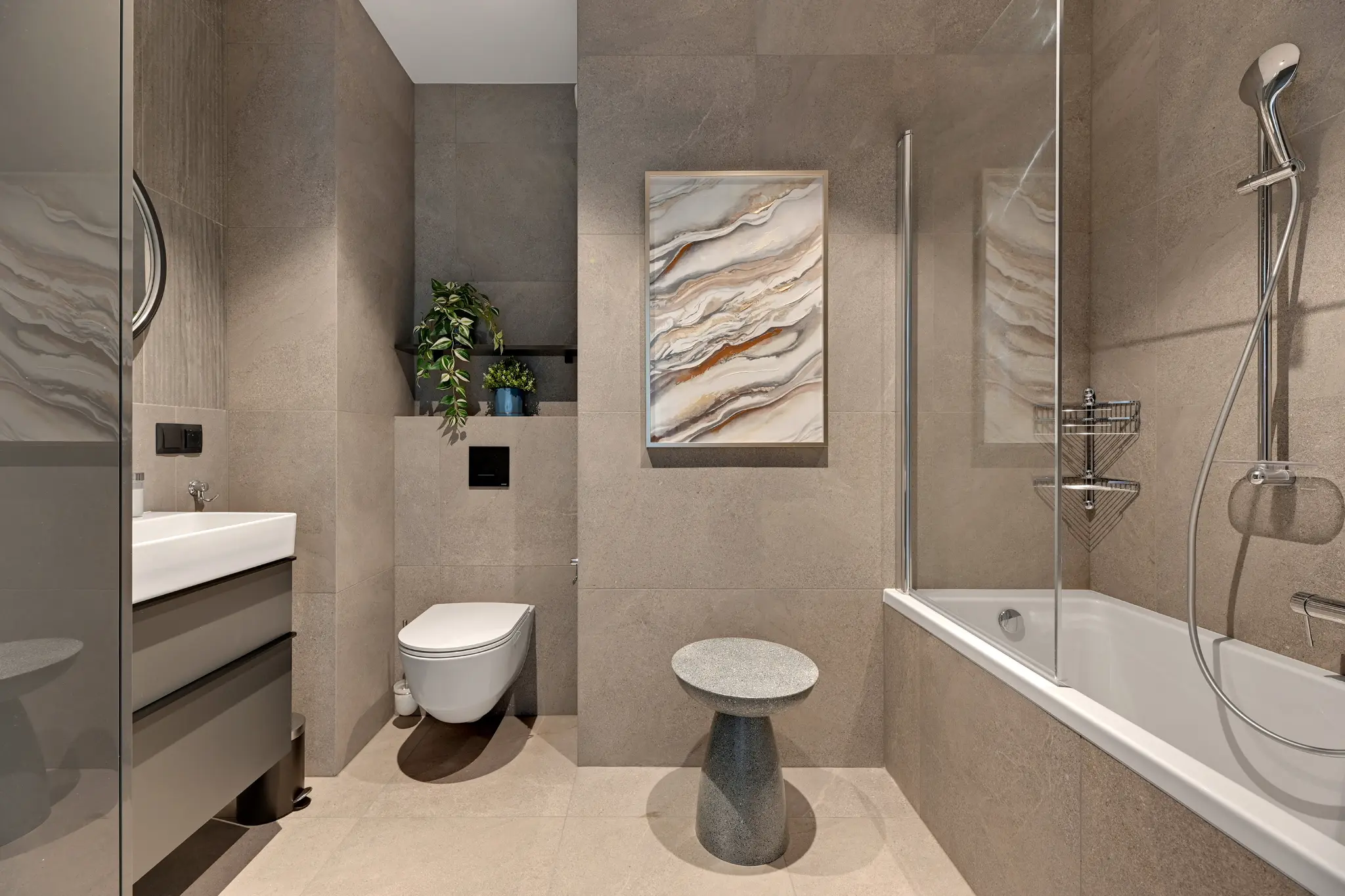 Bathroom in a Scala apartment — a bathtub with a glass screen, washbasin and beige-grey tiles