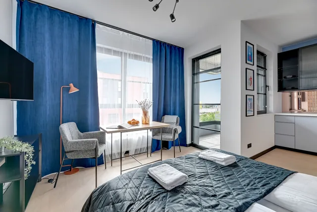 DOKI Living — stół przy oknie i część sypialna apartamentu